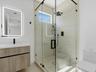 Bathroom featuring a floating wood-finish vanity, illuminated wall mirror, and walk-in shower with floor-to-ceiling tile, glass enclosure, and matte b