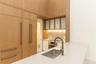 Floor-to-ceiling wood-finish cabinetry, integrated refrigerator, stone countertop with waterfall edge, undermount stainless steel sink, and glass-pane