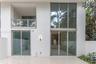 Exterior elevation featuring expansive two-story floor-to-ceiling windows, a covered balcony with a glass railing, large-format tile patio flooring, a