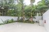 Outdoor courtyard featuring large-format tile flooring, built-in masonry counter with sink, solid perimeter wall, and established landscaping with mat