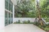 Patio featuring oversized light-toned tile flooring, floor-to-ceiling windows, white perimeter wall, and established perimeter landscaping