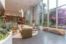Double-height floor-to-ceiling windows, dark stone flooring, exposed concrete structural column, recessed ceiling lighting, and built-in wood-veneer c