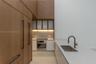 Kitchen featuring full-height wood-finish cabinetry, white solid surface countertops, a stainless steel wall oven, an integrated cooktop, and an under