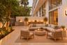 Private patio featuring stone tile flooring, a built-in outdoor kitchen with stainless steel grill, tall privacy walls, and full-height glass sliding 