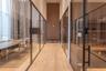 Hallway featuring full-height glass partitions with matte black framing, wood-finish flooring, high ceilings, and built-in shelving