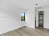 Neutral-toned interior featuring wood-finish flooring, recessed lighting, a single-pane black-trimmed window, and a walk-in closet with built-in shelv