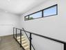 Staircase featuring glass panels with black metal railings, wood-finish flooring, recessed ceiling lighting, and a horizontal clerestory window