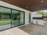 Covered patio featuring large-format stone-finish tile flooring, slatted wood-tone ceiling with recessed lighting, multi-panel sliding glass doors, an