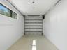 Finished garage featuring smooth white walls, high-gloss epoxy flooring, a horizontal window, and a metal roll-up door