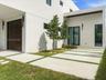 Modern exterior featuring a smooth stucco facade, a dark-finished panel garage door, architectural linear wall-mounted lighting, a paved driveway with