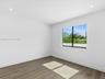Neutral-toned wood-finish flooring, recessed lighting, and a single-pane window with black framing