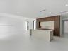 Modern kitchen featuring floor-to-ceiling cabinetry, a central island with stone-finish countertops, recessed lighting, and large-format tile flooring