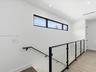Modern staircase featuring a black metal railing with glass panels, wood-finish flooring, recessed lighting, and a horizontal clerestory window