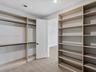 Custom-built cabinetry featuring expansive open shelving, integrated hanging rods, a shaker-style interior door, and neutral wood-finish flooring