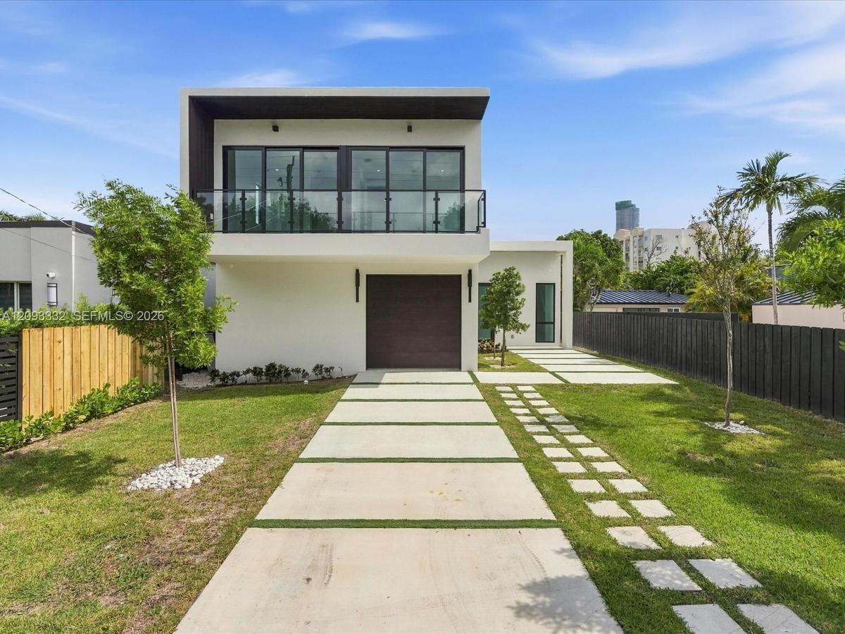 Modern two-story exterior featuring smooth stucco finish, expansive second-level glass balcony with metal railing, single-car garage, and geometric co
