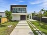 Modern two-story exterior featuring smooth stucco finish, expansive second-level glass balcony with metal railing, single-car garage, and geometric co