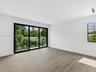 Interior space featuring wood-finish flooring, recessed lighting, and expansive floor-to-ceiling sliding glass doors opening to a balcony with a black