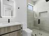 Floating vanity with a light wood-finish cabinetry, rectangular integrated sink, illuminated LED mirror, and matte black hardware