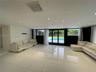 Large-format white tile flooring, recessed ceiling lighting, and multi-panel glass doors opening to an exterior pool area