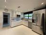 Modern kitchen featuring flat-panel white cabinetry, stainless steel appliances, recessed ceiling lighting, light-toned tile flooring, and a subway-st