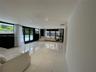 Expansive living area featuring large-format tile flooring, recessed ceiling lighting, and floor-to-ceiling glass sliding doors opening to an outdoor 