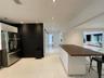 Kitchen featuring a white cabinetry island with a wood-finish countertop, high-gloss large-format tile flooring, stainless steel refrigerator, and rec