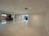 Large-format ceramic tile flooring, recessed ceiling lighting, kitchen island with breakfast bar seating, and sliding barn-style door