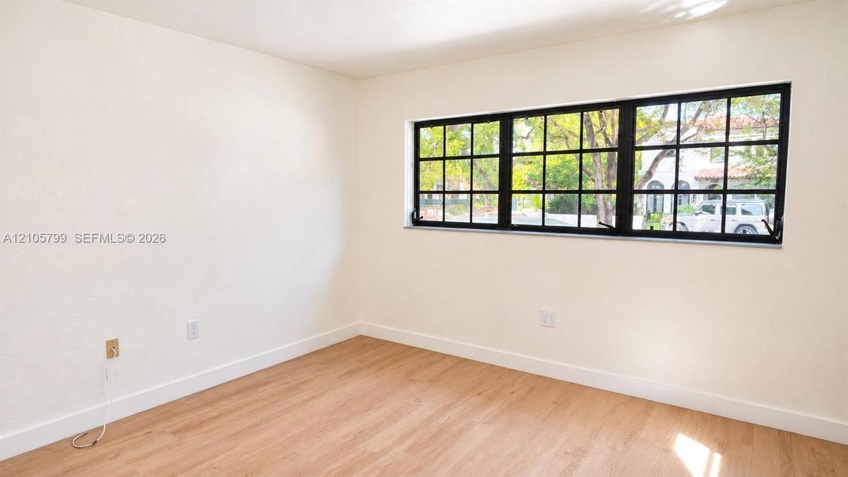 Neutral-toned wall finish featuring wood-finish flooring and a multi-pane window with a black frame