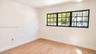 Neutral-toned wall finish featuring wood-finish flooring and a multi-pane window with a black frame