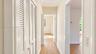 Hallway featuring wood-finish flooring, white louvered-door closets, and arched doorways