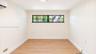 Interior space featuring vertical wood-paneled walls, wood-finish flooring, a wall-mounted ductless climate control unit, and a horizontal multi-pane 