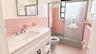Bathroom featuring a white vanity with a composite countertop, ceramic wall tiling, a bathtub with an etched-glass sliding door, and checkered floorin
