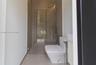 Walk-in shower with frameless glass enclosure, rainfall shower head, handheld sprayer, floor-to-ceiling tile, and wall-mounted dual-flush toilet
