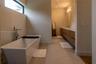 Freestanding soaking tub with floor-mounted faucet, horizontal clerestory window, dual-sink vanity with wood-finish cabinetry, and neutral large-forma