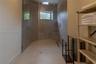 Walk-in shower featuring a glass enclosure, wall-mounted rain shower head, built-in tiled bench, recessed wall shelving, and a linear floor drain