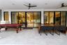 Covered patio featuring large-format stone floor tiles, expansive black-framed sliding glass doors, and dual ceiling fans