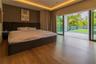 Wood-finish flooring, recessed tray ceiling with integrated cove lighting, and large-format glass sliding doors opening to a glass-railed balcony
