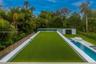 Backyard featuring a synthetic turf rooftop, swimming pool with integrated spa, paved terrace, and wood-paneled privacy fencing