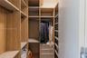 Custom reach-in closet featuring wood-finish cabinetry, built-in shelving, integrated garment rods, and a stack of three storage drawers