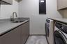 Utility room featuring matte-finish cabinetry, stone-composite countertops, an integrated stainless steel sink with a high-arch faucet, and overhead s