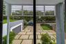 Exterior covered balcony featuring horizontal slatted privacy screens, overlooking a geometric paver driveway with turf accents and a modern flat-roof