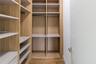 Customized walk-in closet featuring floor-to-ceiling wood-finish shelving, multi-level hanging rods, built-in drawer units, and wood-finish flooring