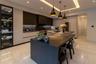 Gourmet kitchen featuring flat-panel cabinetry, a central waterfall-edge island, stone-surfaced countertops, custom recessed tray ceiling lighting, an