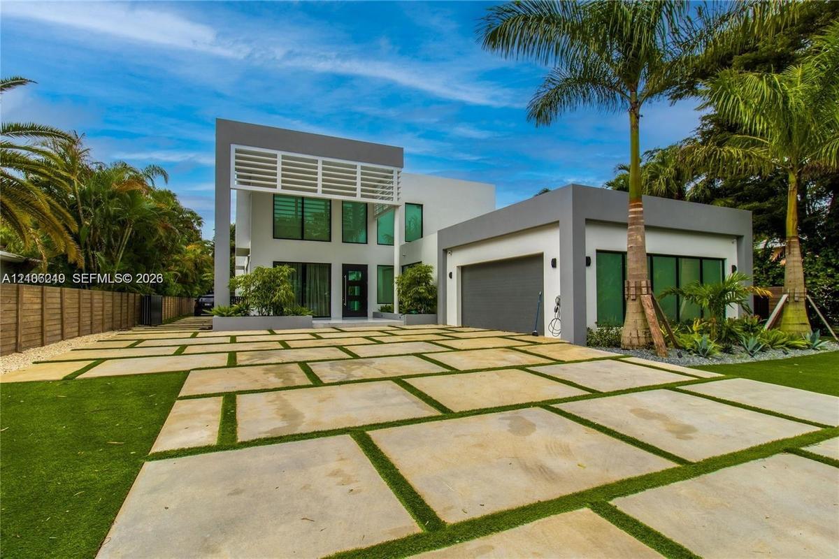 Contemporary multi-level exterior featuring clean geometric lines, large-format concrete paver driveway with turf accents, high-profile louvered archi