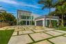 Contemporary multi-level exterior featuring clean geometric lines, large-format concrete paver driveway with turf accents, high-profile louvered archi