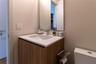 Wood-finish vanity cabinet with a white countertop, integrated sink, polished chrome faucet, and rectangular wall-mounted mirror