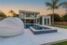 Contemporary exterior featuring a two-story structure, expansive pool, elevated spa with tile cladding, covered patio area, and vertical garden wall