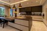 Gourmet kitchen featuring a large central island with stone-finish countertops, matte-finish cabinetry, built-in dual wall ovens, and custom pendant l