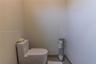 Minimalist space featuring a dual-flush toilet with a seamless base and neutral tile flooring