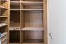 Custom wood-finish closet system featuring integrated shelving, hanging rods, and built-in drawer units with a flat-panel design